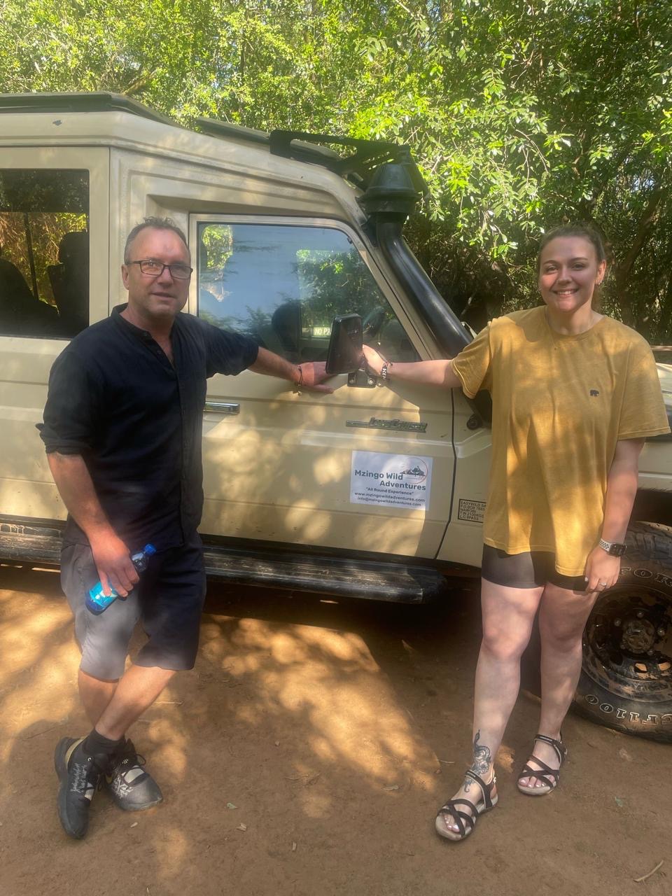 Guests celebrating beside their Mzingo safari vehicle