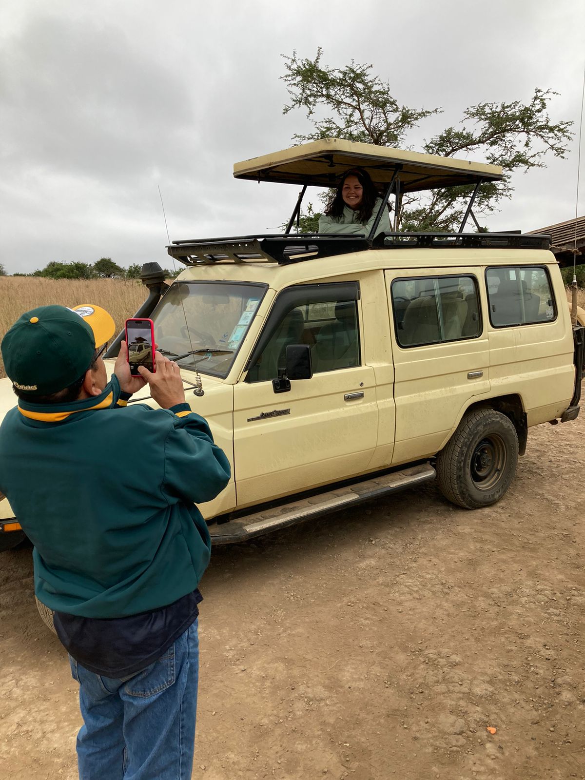 A guest framed in the roof hatch of a safari vehicle