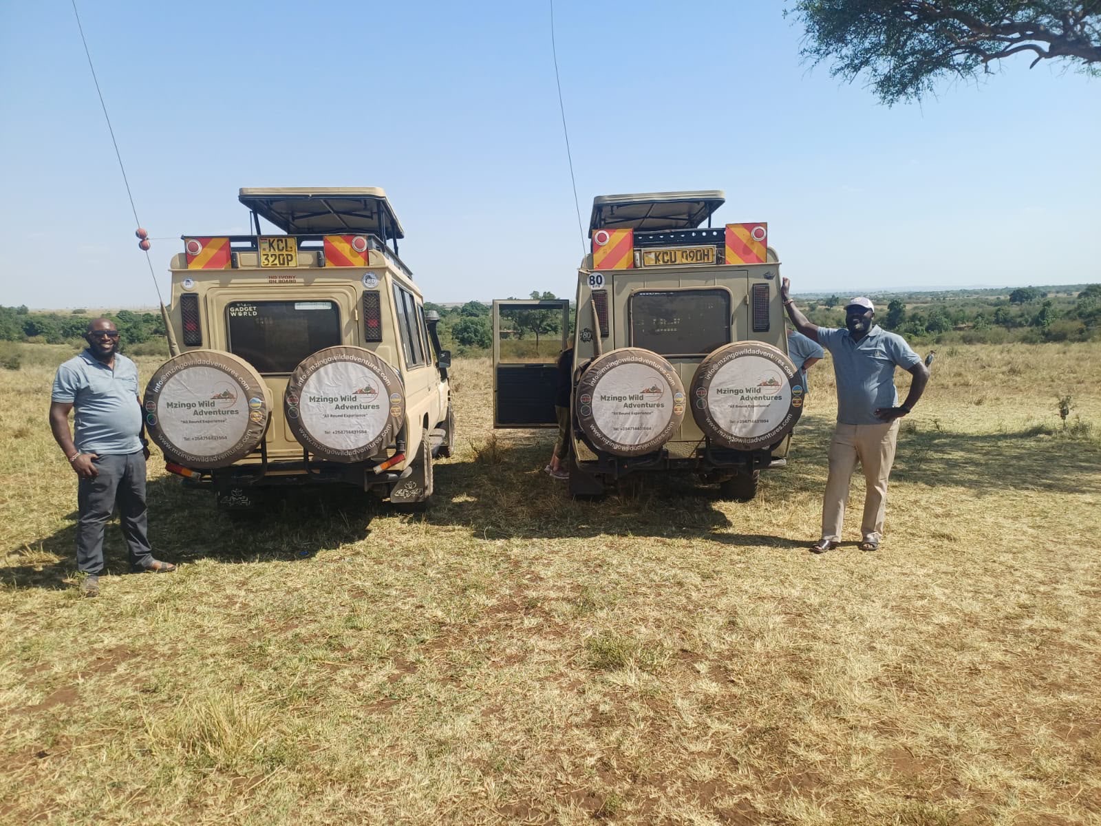 Two branded Mzingo safari vehicles with their guides on the savanna